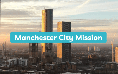 Manchester City Mission logo above a photo of the city's skyscrapers